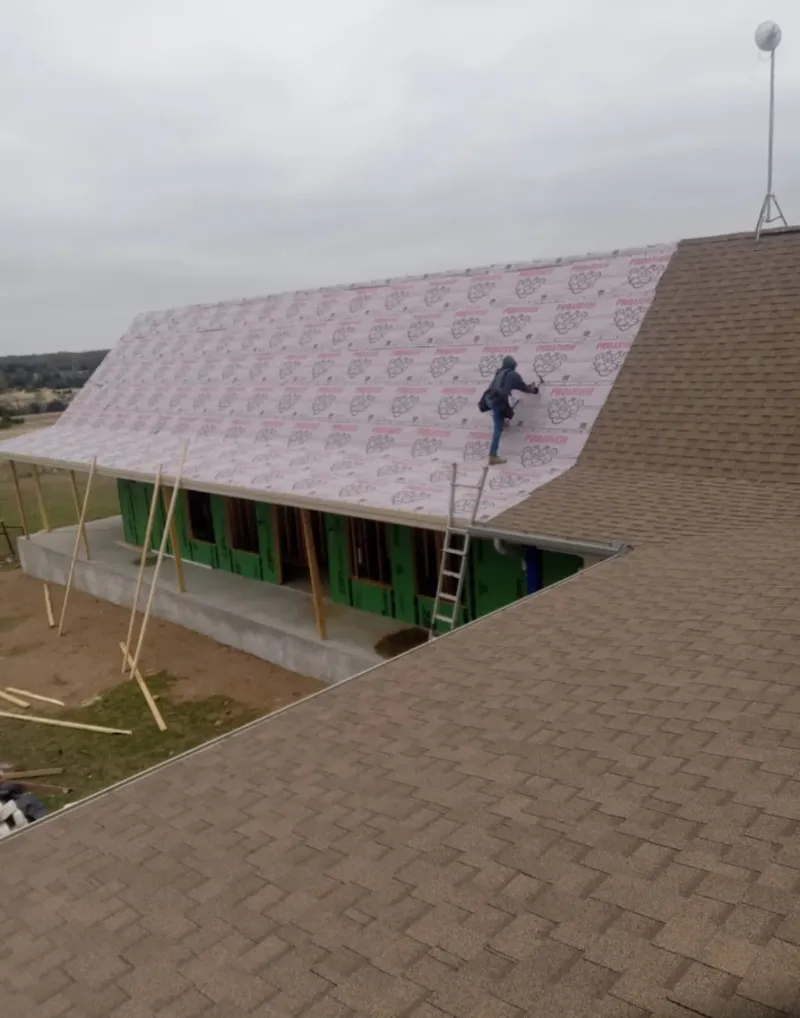 Worker preparing underlayment for a metal roof installation in South Huntingdon